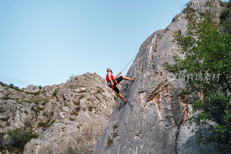 男子攀爬在陡峭的悬崖岩壁上