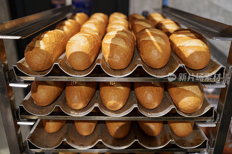 在面包店厨房的冷却架上，新鲜出炉的脆皮法棍面包的特写镜头