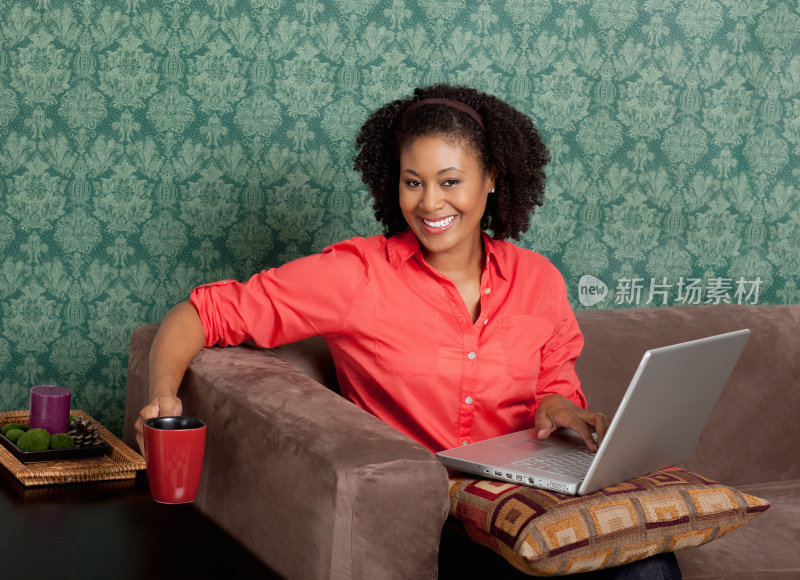 轻松的女人浏览互联网，因为她喝咖啡