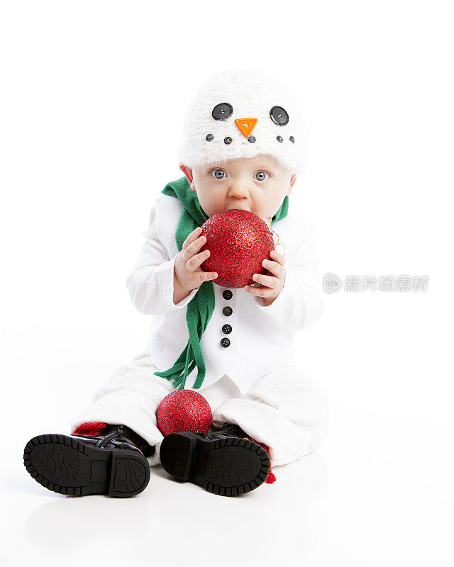 长牙的婴儿男孩穿着雪人服装咀嚼圣诞恩