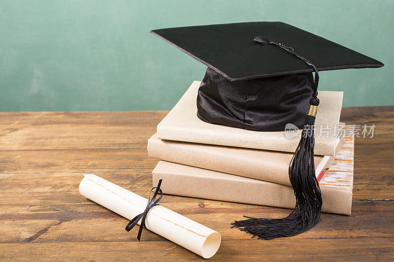 毕业!学士帽，学士帽和流苏，学位证书摆在桌上。教育。