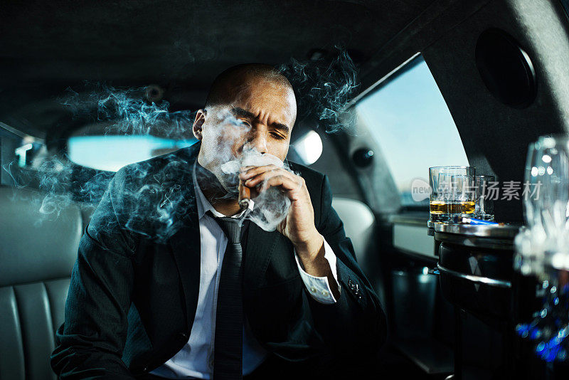 在豪华轿车里抽雪茄的商人。