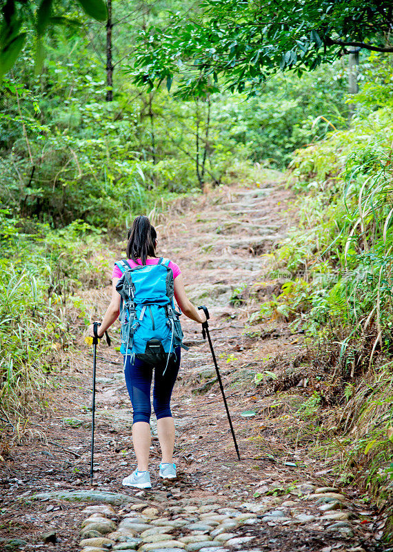 在树林里背着背包的年轻女性徒步旅行者