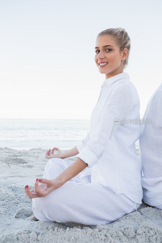 金发女人坐在瑜伽莲花的位置对着镜头微笑