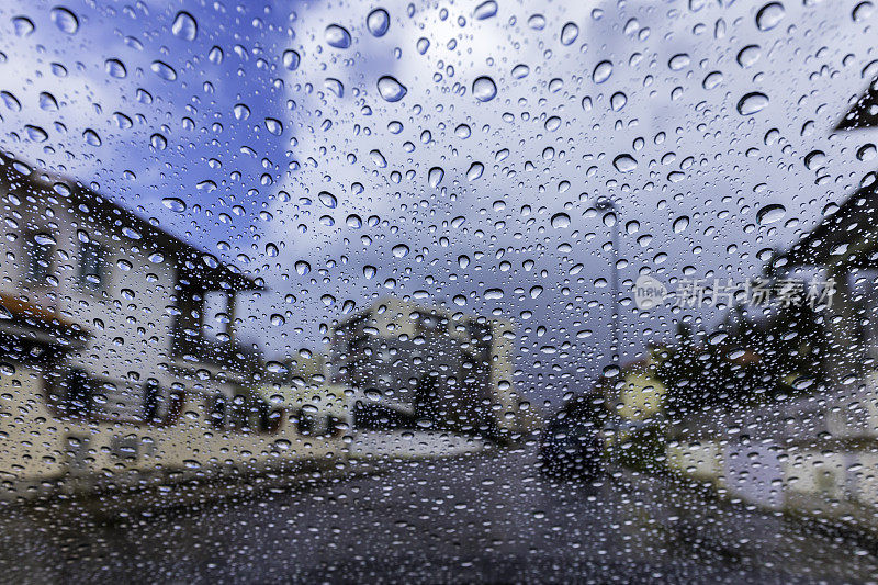 雨点落在带有街景的挡风玻璃上