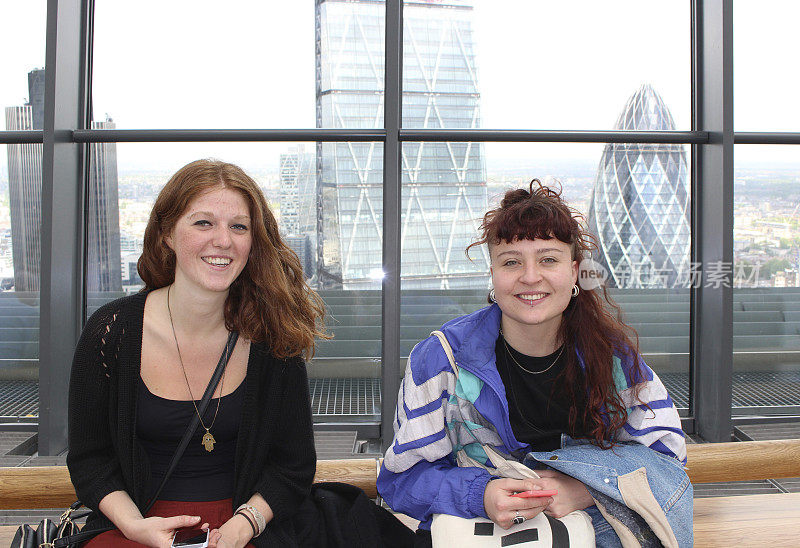 英国伦敦，年轻女子在摩天大楼拍照