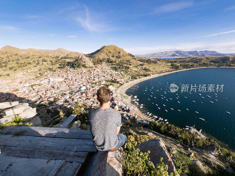 一个年轻人坐在秘鲁的喀喀湖科帕卡巴纳市美丽的风景中