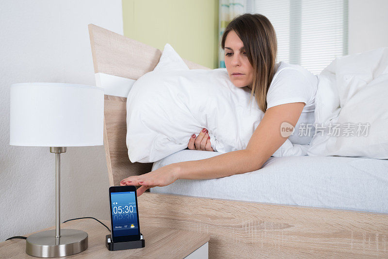 女人在床上用手机闹铃