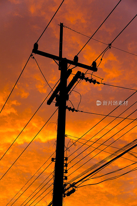 橙色的天空映衬着高压电线的轮廓