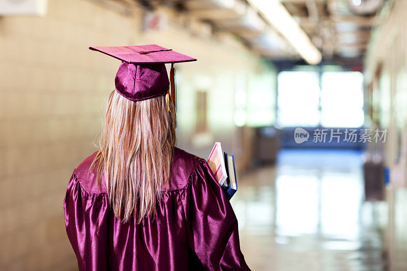 在学校穿着毕业礼服的年轻女学生