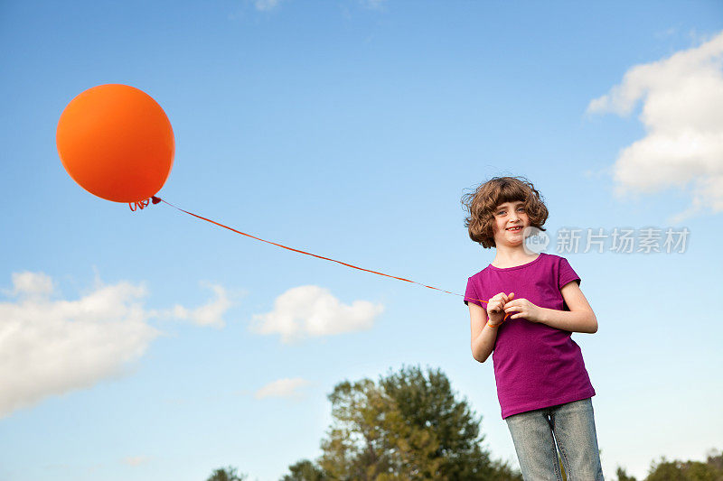 快乐的年轻女孩拿着一个气球在外面