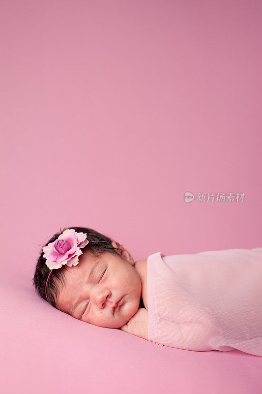 熟睡的新生女婴在粉红色背景与复制空间