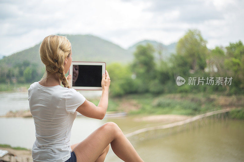 女孩在河边用平板电脑拍照