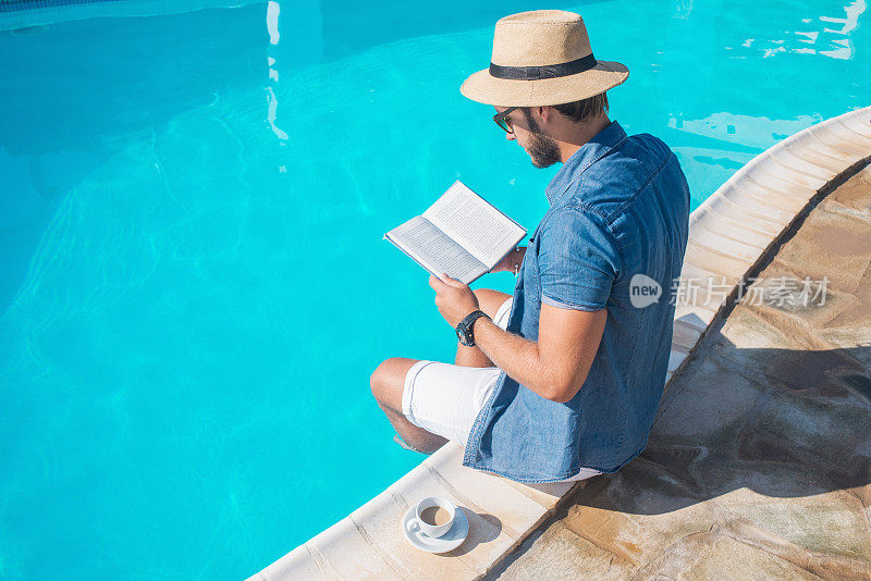 一个在泳池边看书的男人