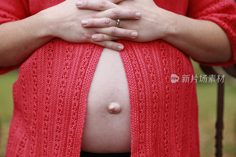 孕妇的肚子在敞开的毛衣