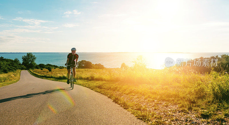 在夕阳西下，自行车赛选手骑着自行车爬上陡峭的山坡