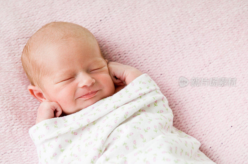 微笑着睡着的新生女婴裹在毯子里