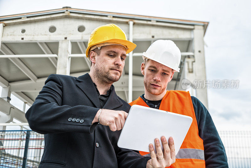 建筑师和建筑工人在平板电脑上看蓝图