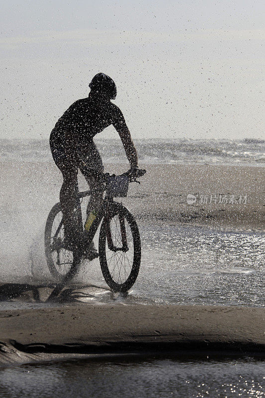 一个骑自行车的人的剪影穿过海水