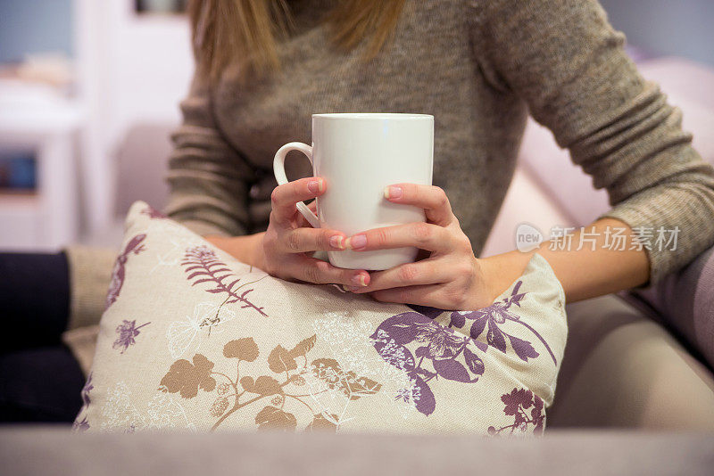 女人的手捧着一杯白色的咖啡或茶