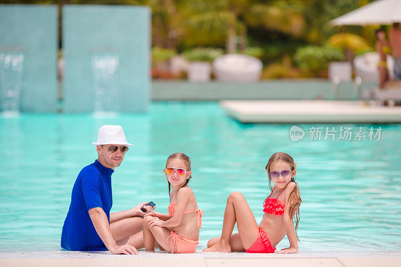 小女孩和快乐的爸爸在游泳池边玩
