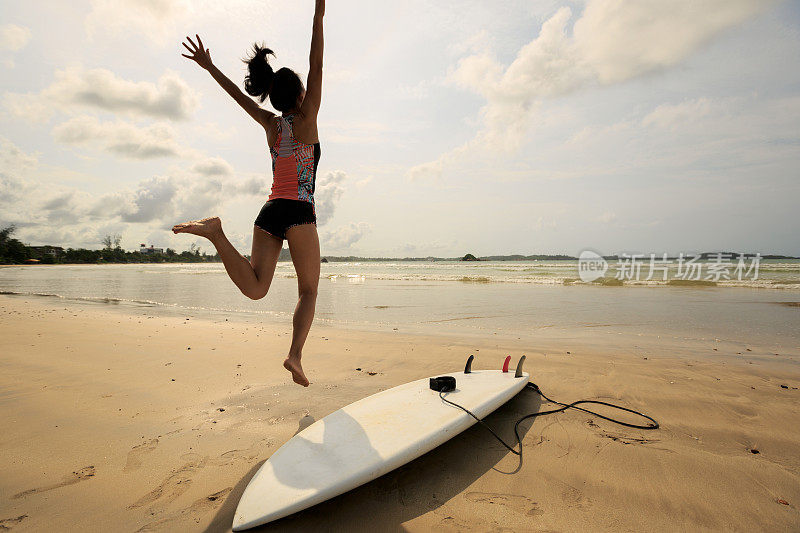 年轻女子冲浪者在海滩上热身