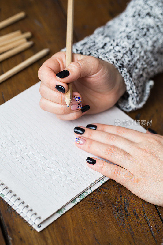 一个修了漂亮指甲的女人在笔记本上画画