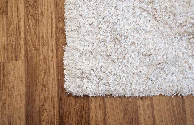 在客厅的强化木地板上的特写白色地毯，室内装饰