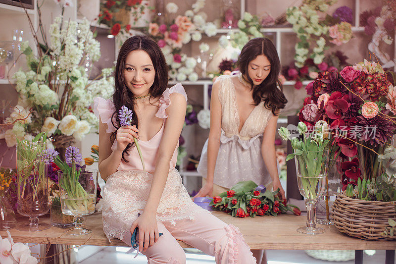 美丽的亚洲女性花匠快乐工作在花店与许多春天的花