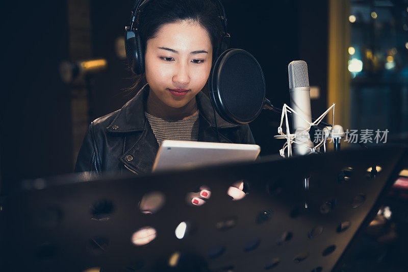 亚洲女孩在录音棚里拿着平板电脑唱歌，中国上海