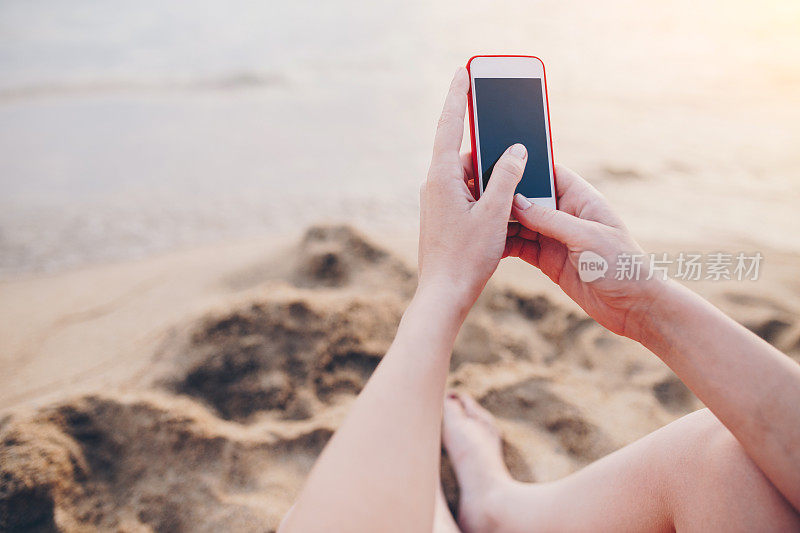 女人在海滩上用手机的特写