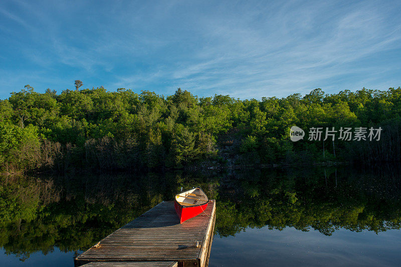 在加拿大清晨的阳光下，码头上的红色独木舟