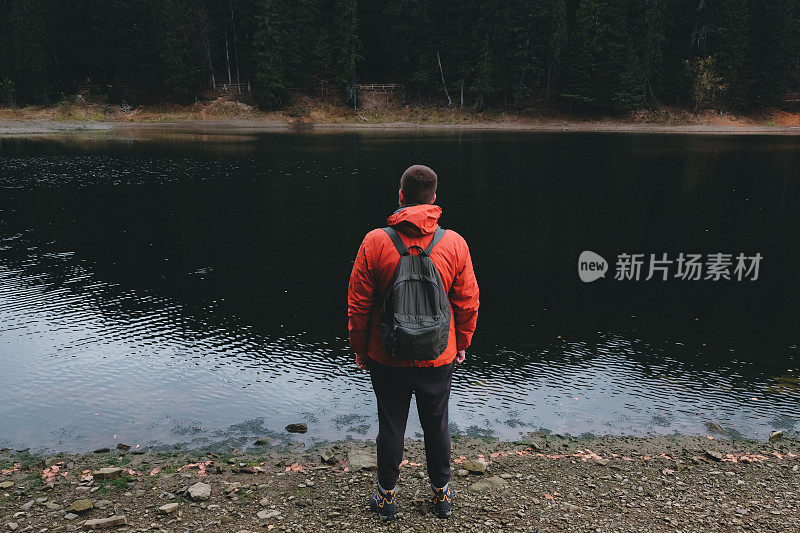 一个背着双肩包的男人，在山湖上游逛