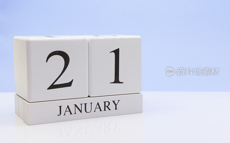 1月21日。月21日，日历在白色的桌子上反射，以浅蓝色为背景。冬天的时候，空白的文字