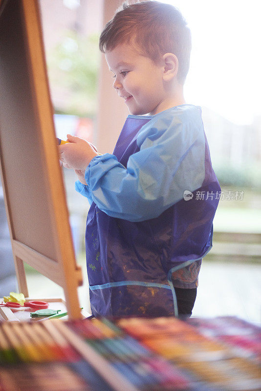 微笑的幼童在画架上作画