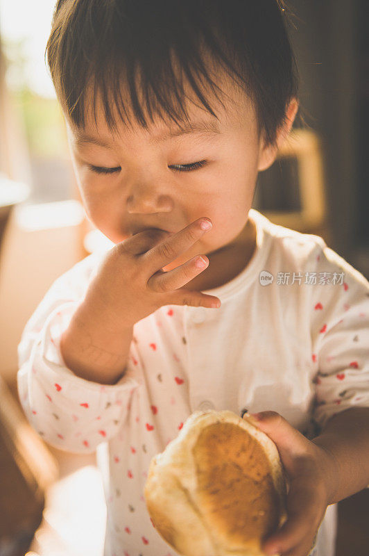 一个亚洲小女孩吃面包