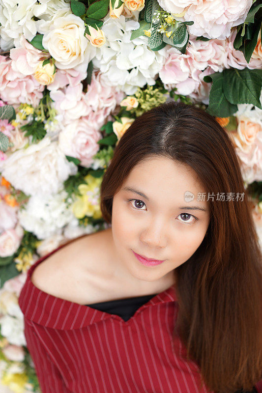 美丽的亚洲年轻女孩与新鲜干净的皮肤和漂亮的眼睛在玫瑰花香的背景。