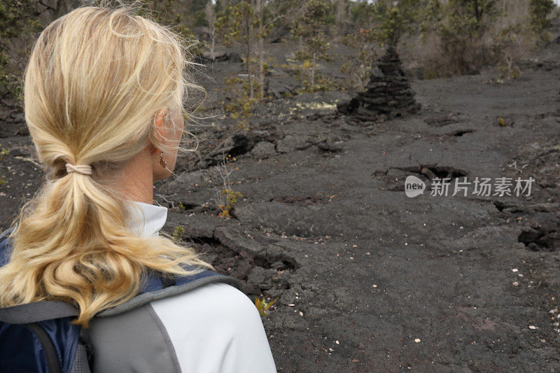 女性徒步旅行者沿着火山熔岩向前走