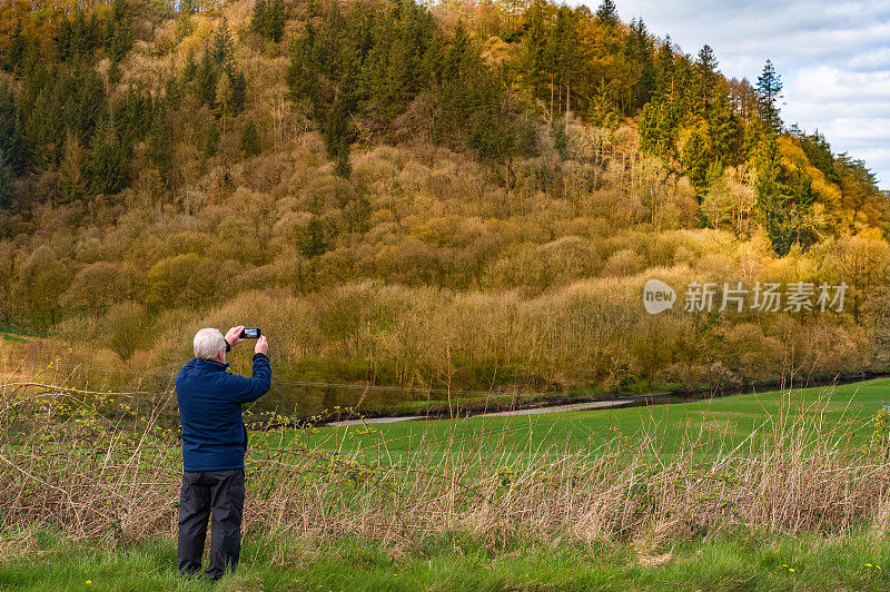 活跃的老年人在农村背景下用手机拍照