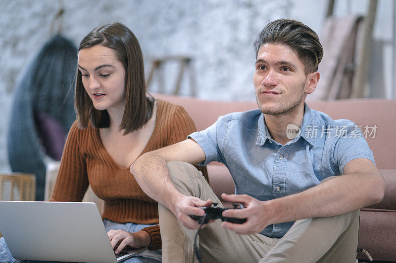 千禧一代情侣在笔记本电脑上玩游戏和工作