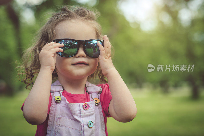 快乐的小女孩戴太阳镜在春天或夏天的户外