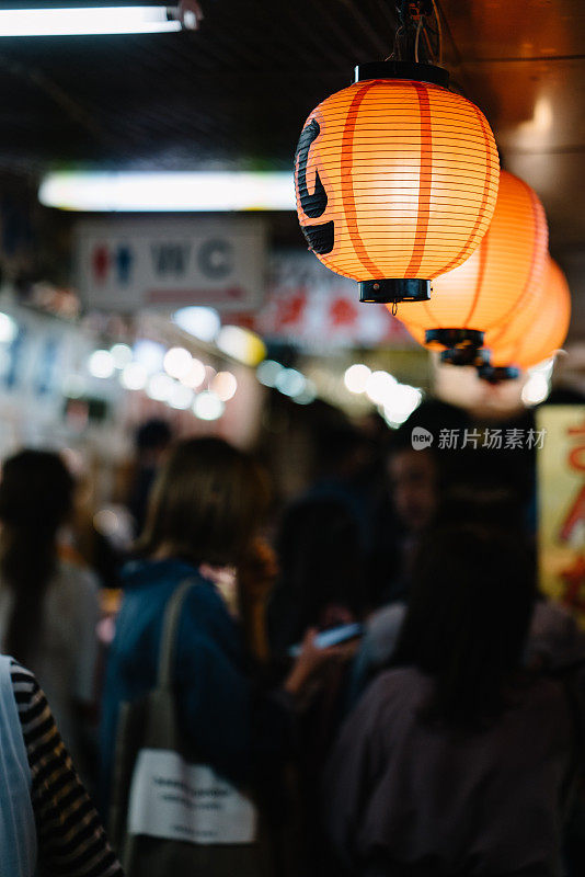 一排日本灯笼在拥挤的市场上悬挂着
