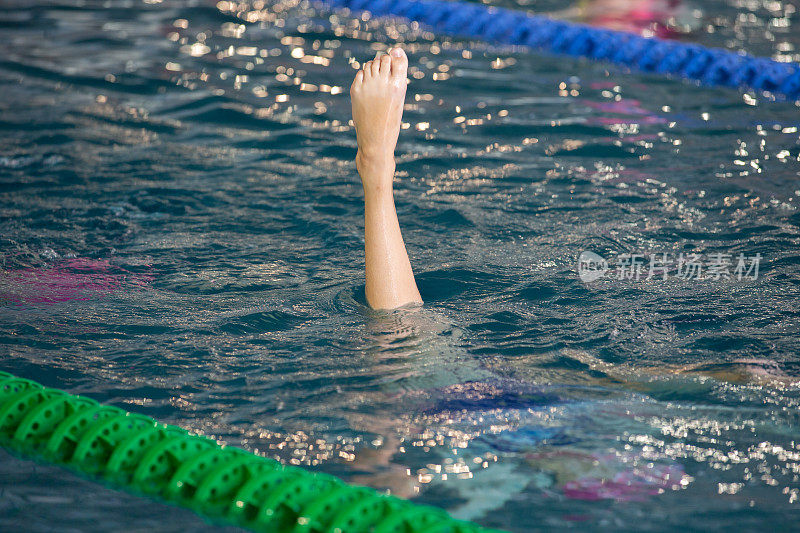 花样游泳运动员在动作中指出水面。花样游泳运动员的腿部运动。花样游泳队在水中表演一套同步的复杂动作。