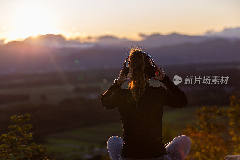 女孩戴着耳机在夕阳下听音乐