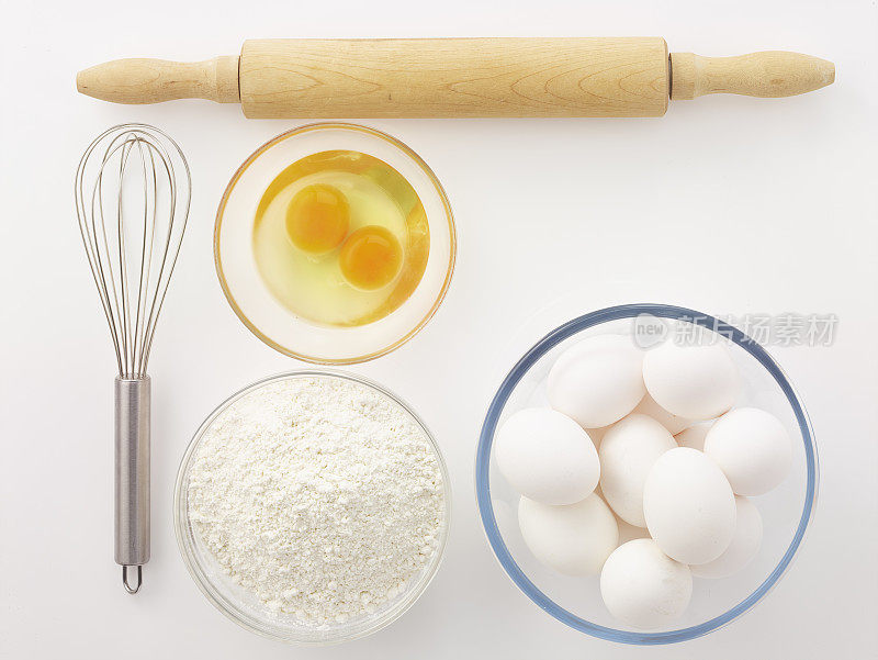 鸡蛋，打蛋器，面粉和擀面杖在白色的背景