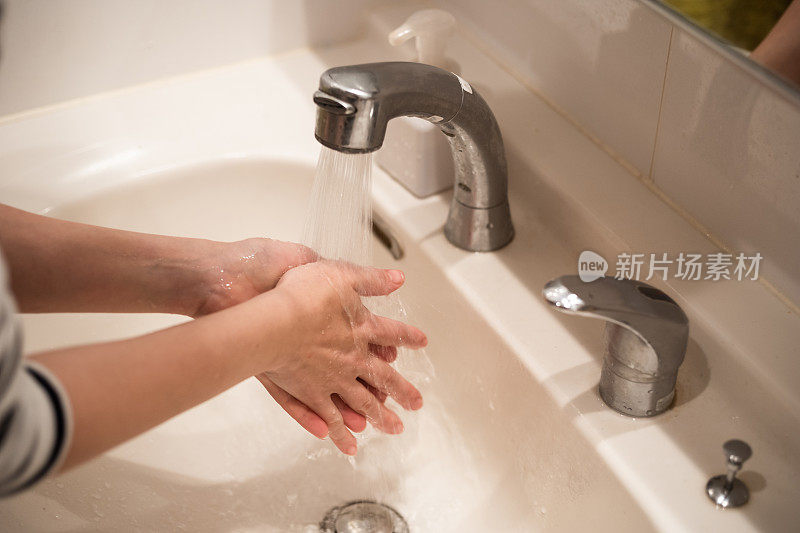 亚洲妇女在洗手盆洗手的照片