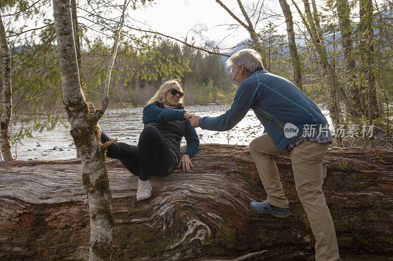 一对成熟的夫妇在河边的原木上放松