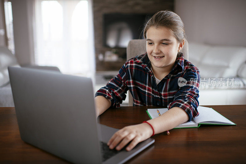 年轻女孩坐在卧室书桌前用笔记本电脑做作业