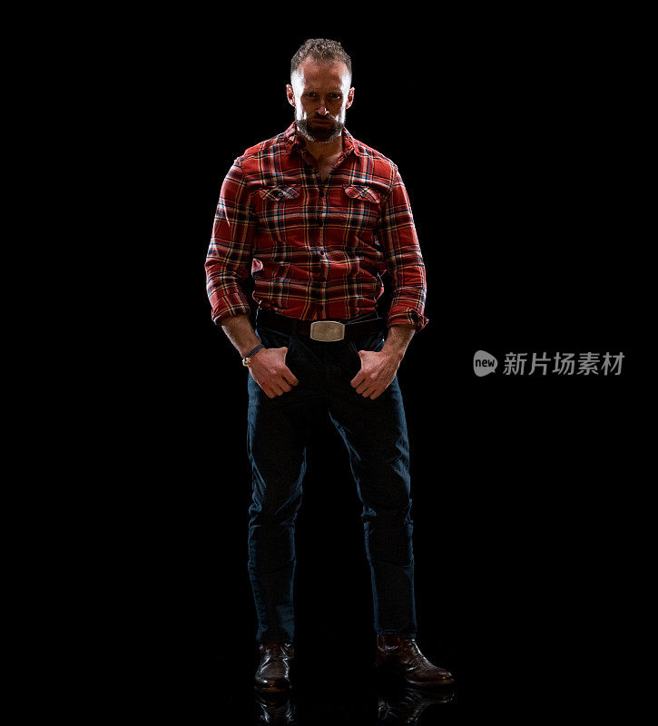 白人男性脱衣舞娘站在前面的黑色背景穿着格子衬衫