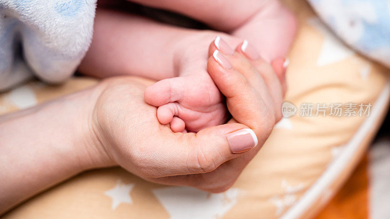 妈妈的手牵着可爱的宝宝的脚特写
